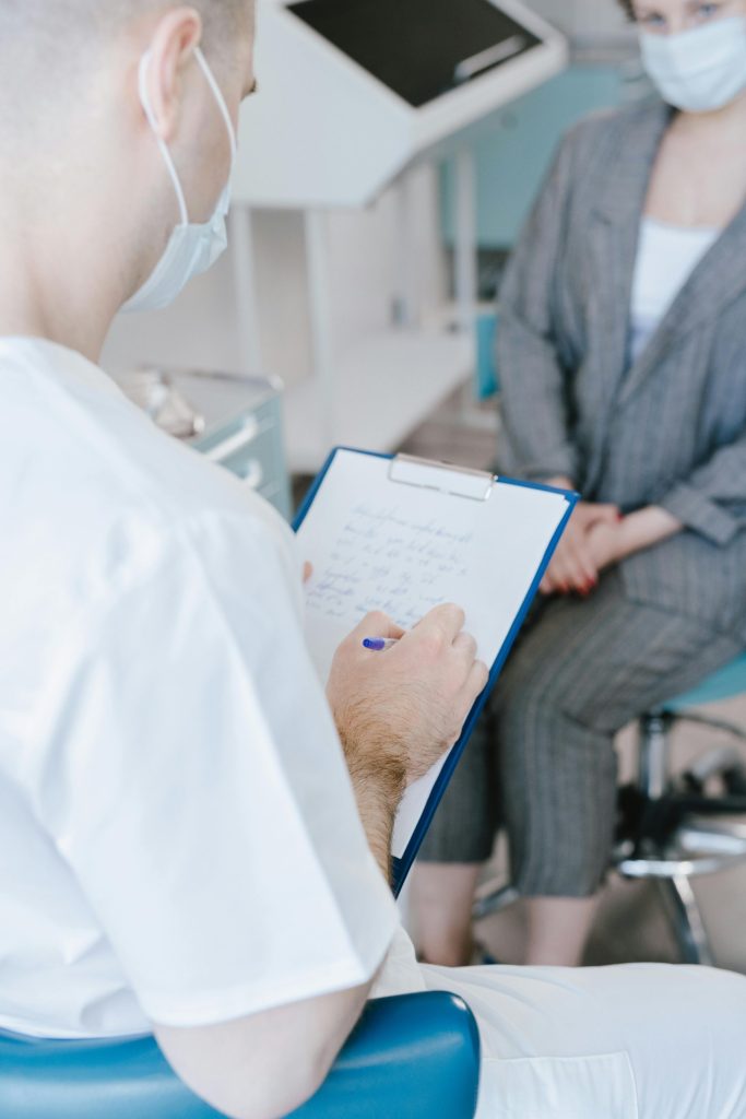 Ein medizinischer Fachmann macht sich während der Beratung eines Patienten in einer klinischen Umgebung Notizen.