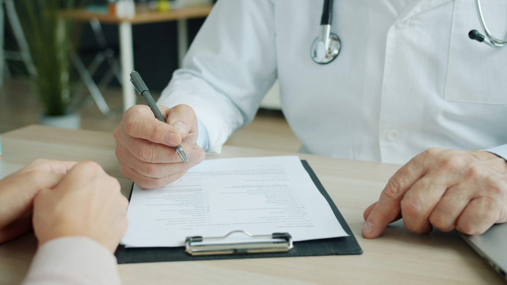 Arzt schreibt in die Krankenakte eines Patienten